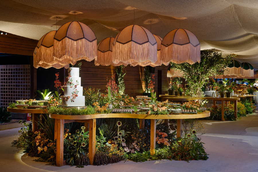 Mesa de doces no formato orgânico, com design floral com texturas e lustres em tecido